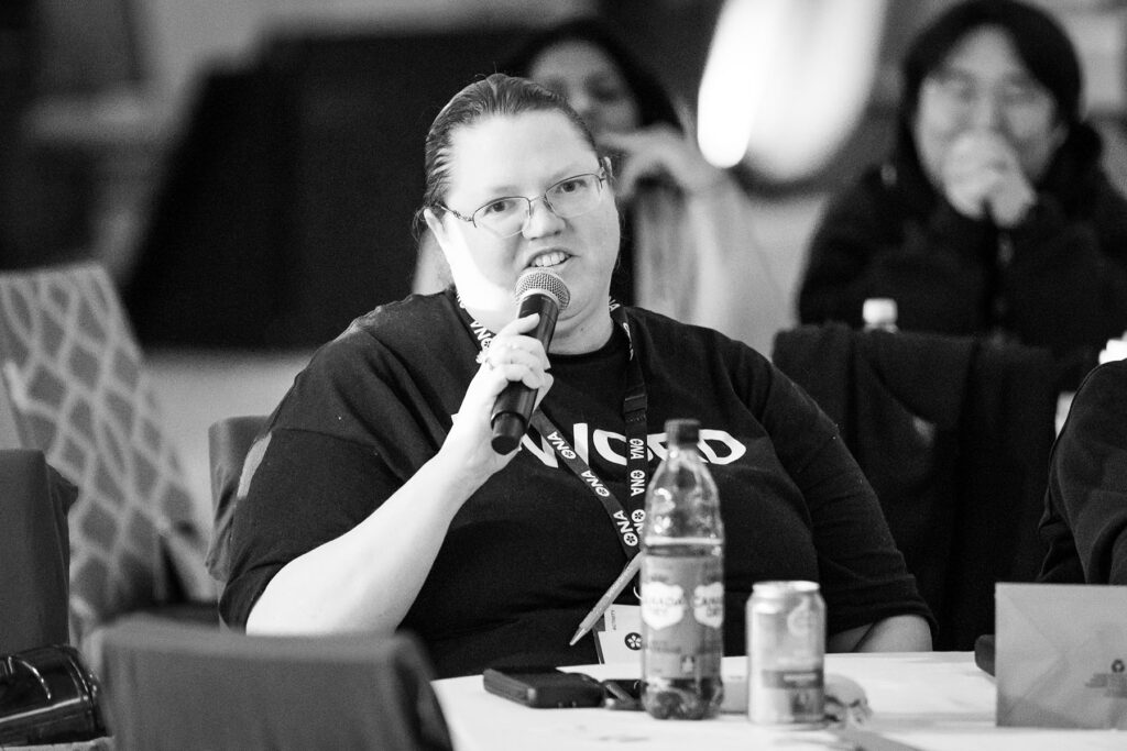 Member sitting at a table with others talks into a mic.