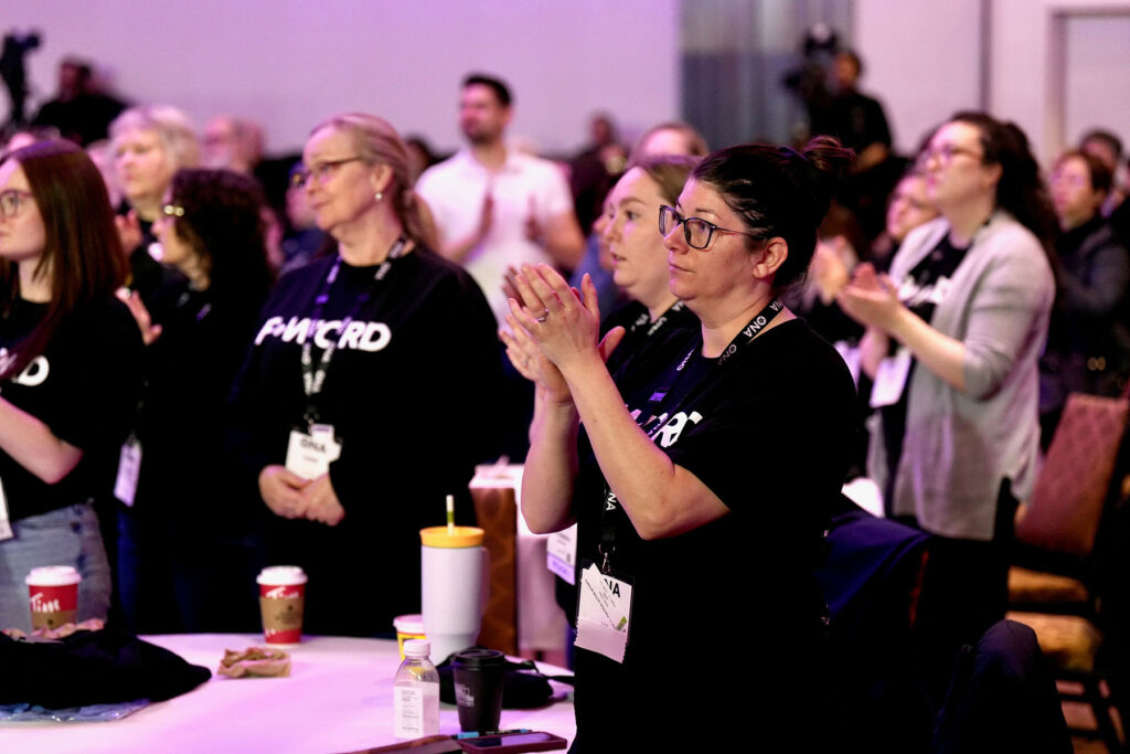 Members stand at meeting and clap.