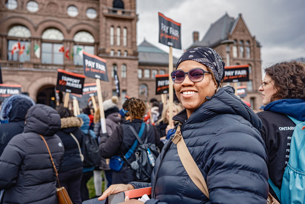 Member smiles at camera with other ralliers in background.