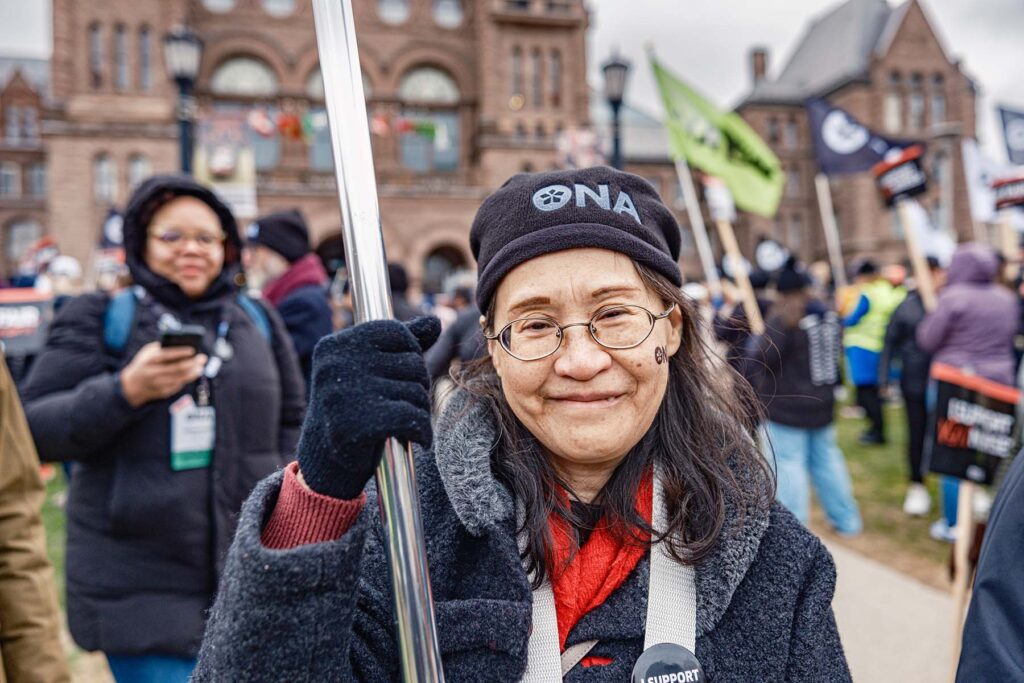 Smiling member at rally holds sign.