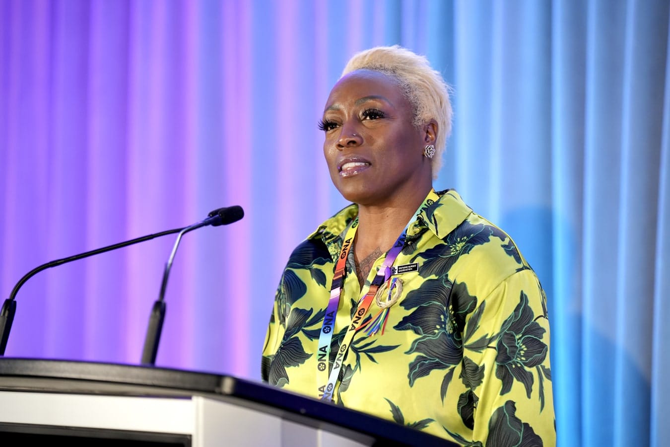 Anti-Racism and Anti-Oppression Team Manager Kieran Maxwell at podium at provincial meeting talks to delegates.