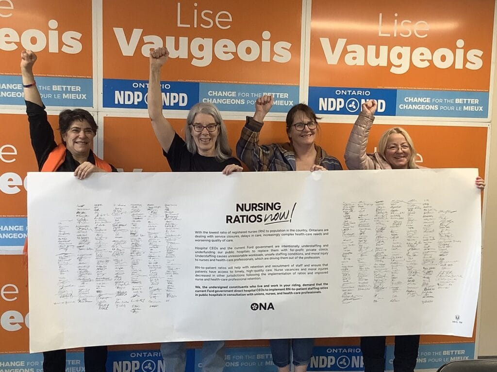 Members and candidate give fist pumps while holding life-sized banner.