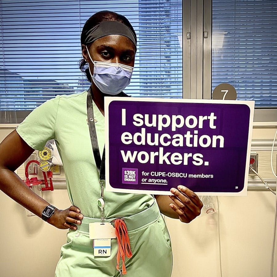 Member in mask holds sign.