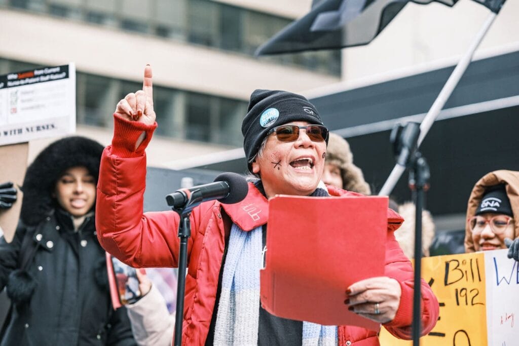 Member Gloria Cardinal Tan speaks into microphone, pointing finger in air.