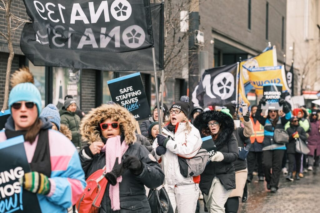 Members march in a line on sidewalk.
