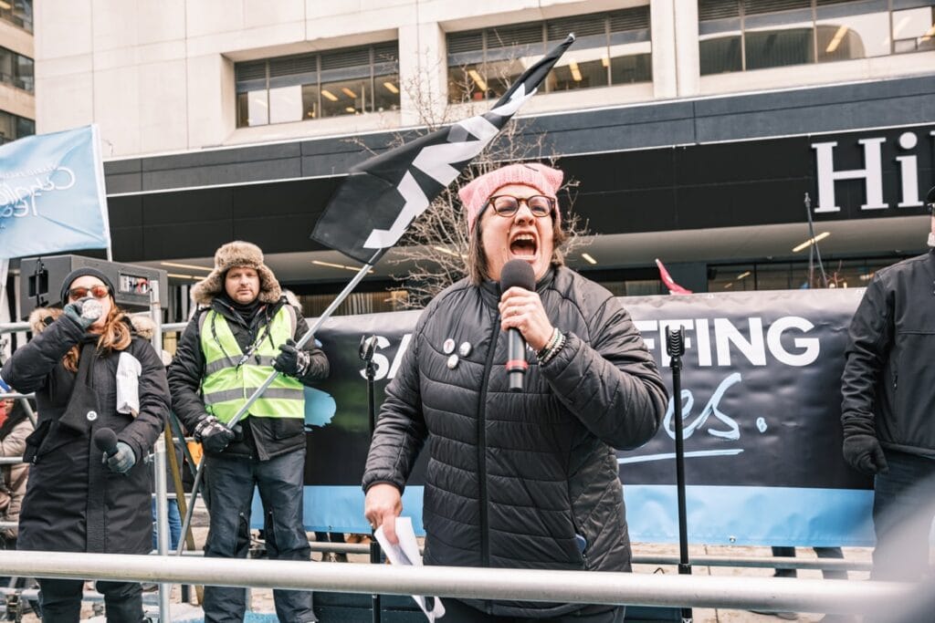 ONA Provincial President Erin Ariss yells into megaphone from flatbed truck.