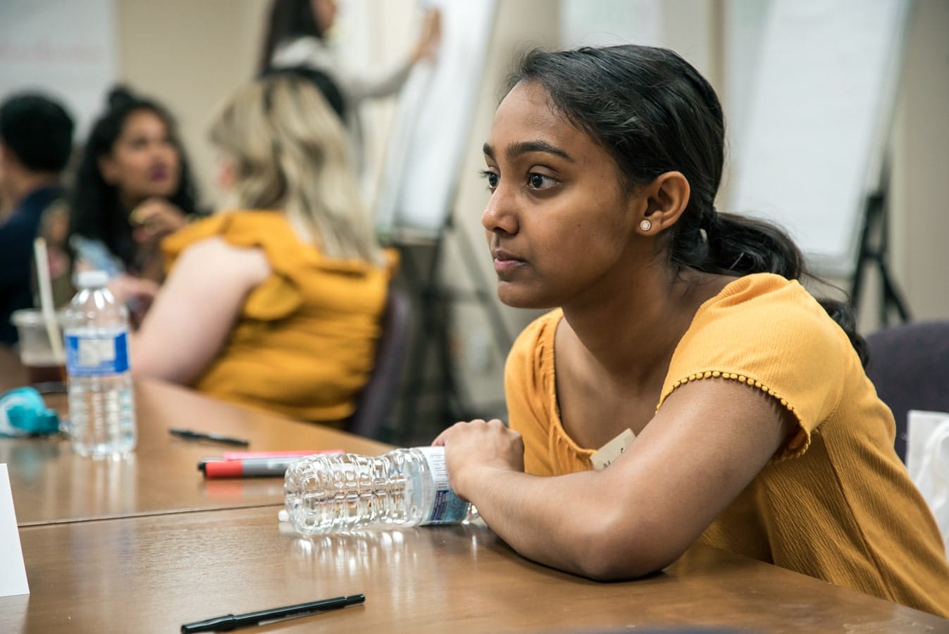 Nursing student sitting at table chatting to someone off camera.