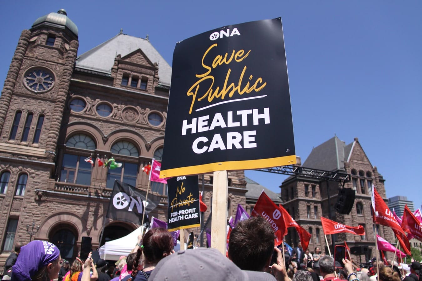 Large crowd, including ONA members holding our signs, rallies at Queen’s Park.