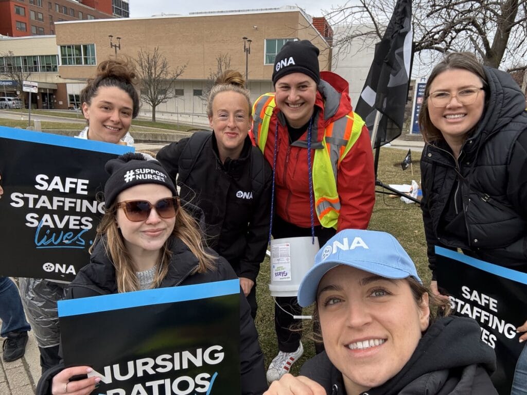 Five smiling members and Board member hold signs.