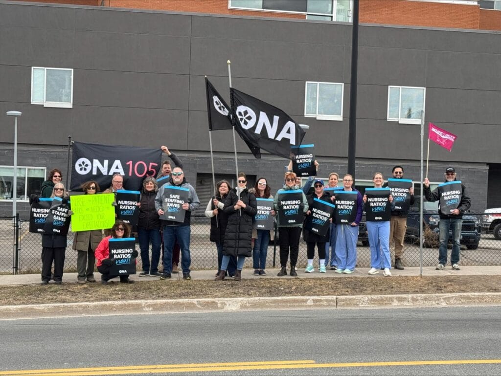 Line of members across a main street show their signs and unions flags.