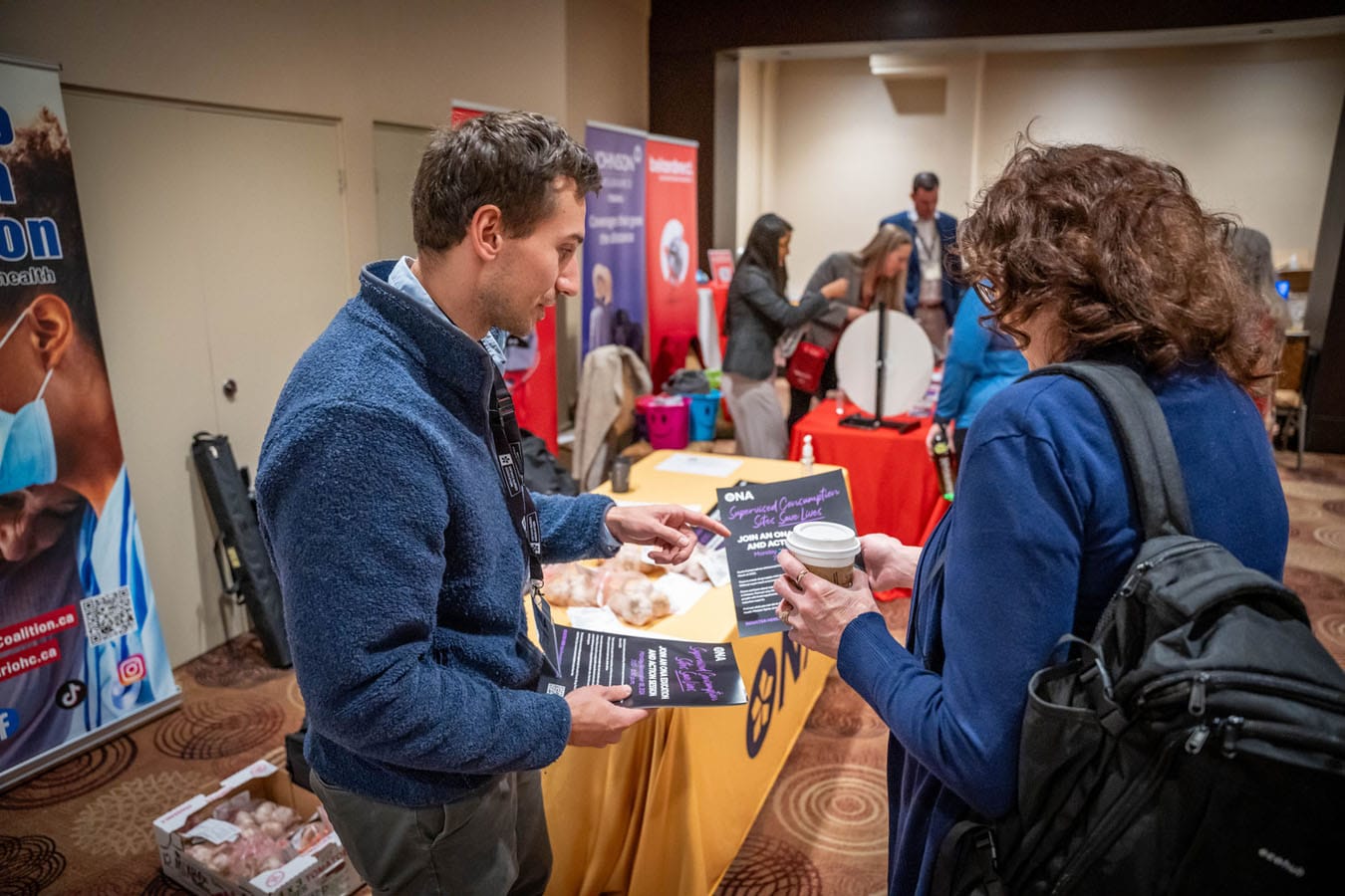 Staff member hands member a flyer on supervised consumption sites.