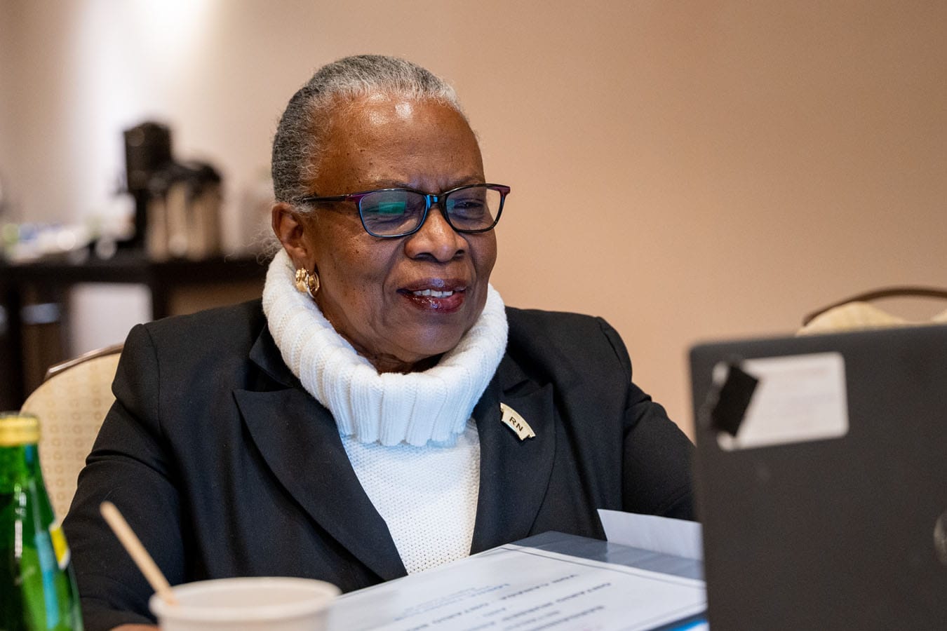 A smiling Lorna Thompson from our Victorian Order of Nurses Provincial Negotiating Team sits at table and looks at laptop.