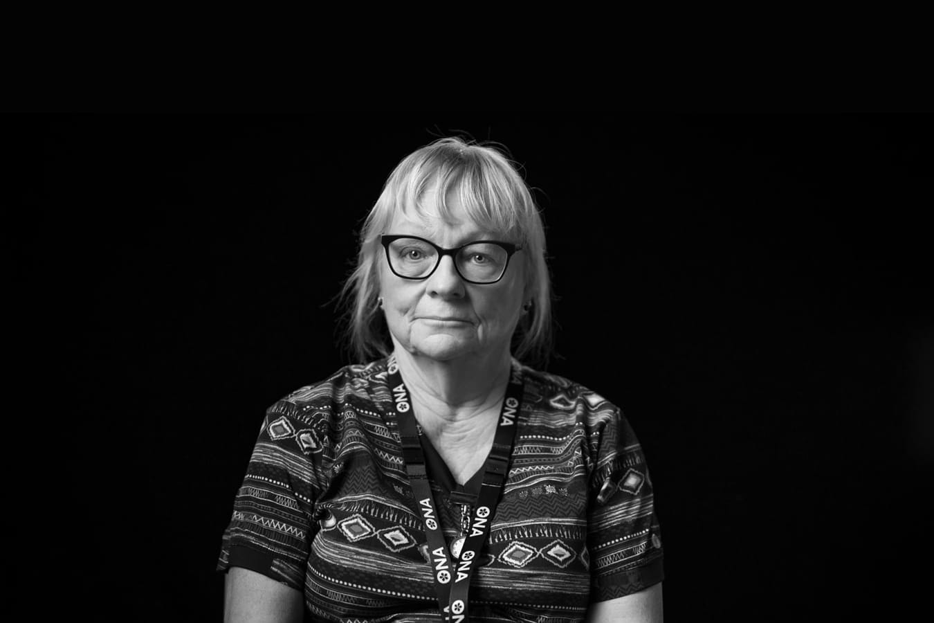 Black and white photo of nurse looking somberly at camera.