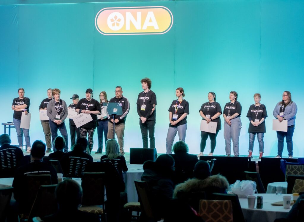 A row of thirteen people standing on a wide stage.