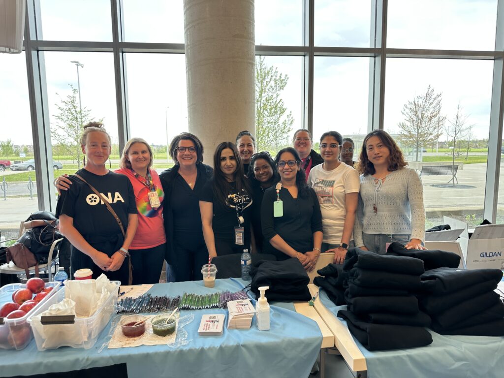 A group of people smile for the camera from behind a table full of ONA merchandise.