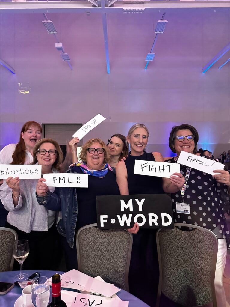 A group of people hold signs with f words, including fantastique, FML, fed up, fight, and fierce.