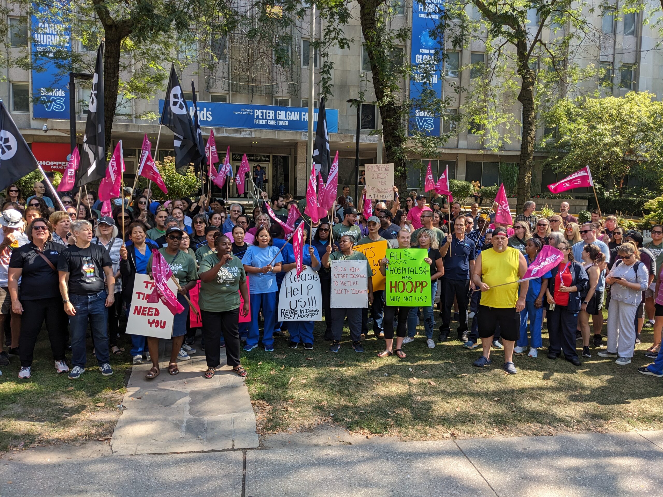 A group of people hold flags in front of SickKids hospital.