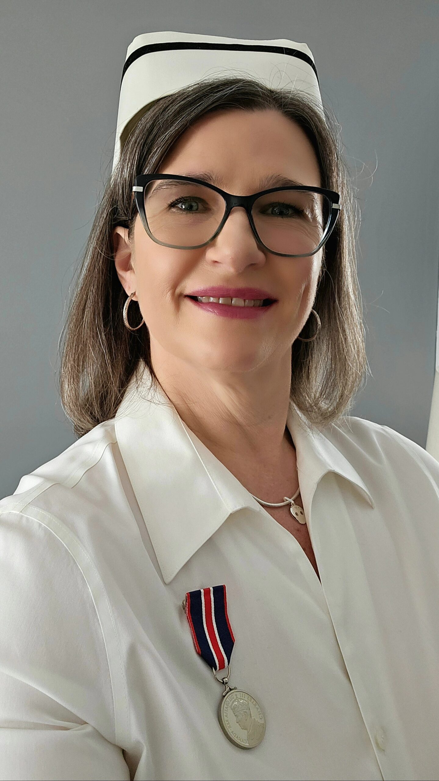 Headshot of member Laura Pella in nurses’ uniform, displaying coronation medal.