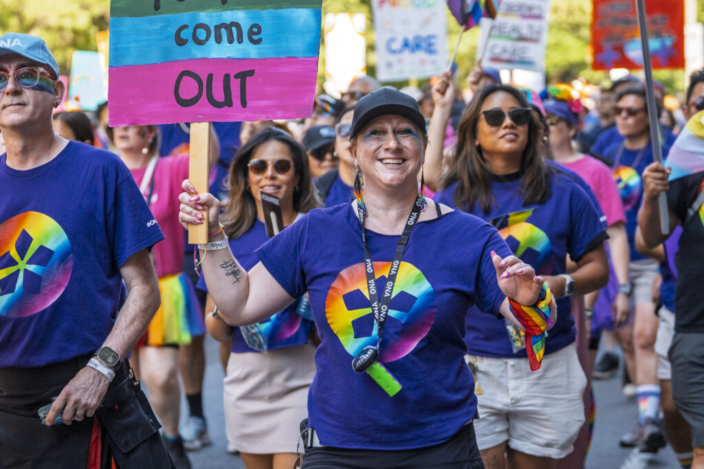 ONA member Cindy Drouin marches in the parade holding a sign a says 