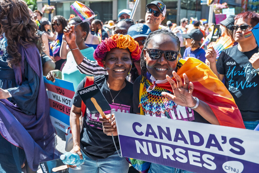 Two members wave to the camera while marching in the parade.