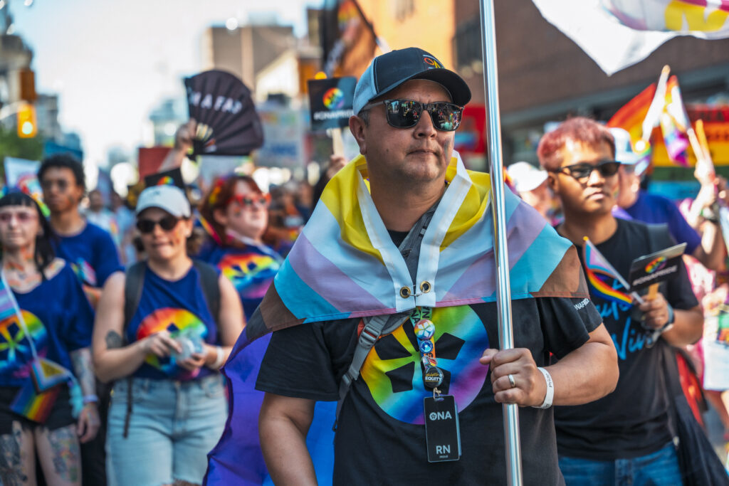 ONA First Vice-President Alan Warrington wears a Pride flag around his shoulders while marching in the parade.
