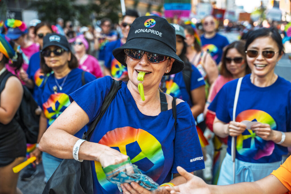 An ONA member hands out stickers to parade-watchers as she blows on a lime-green whistle.