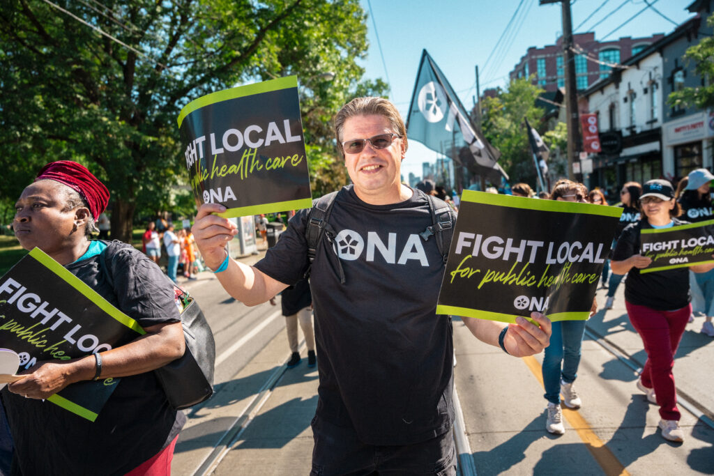 One member holds up two signs while marching in the parade.
