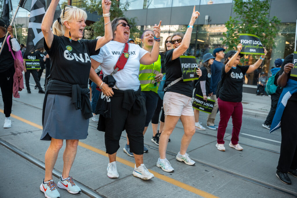 Four people yell emphatically as part of the Labour Day parade.