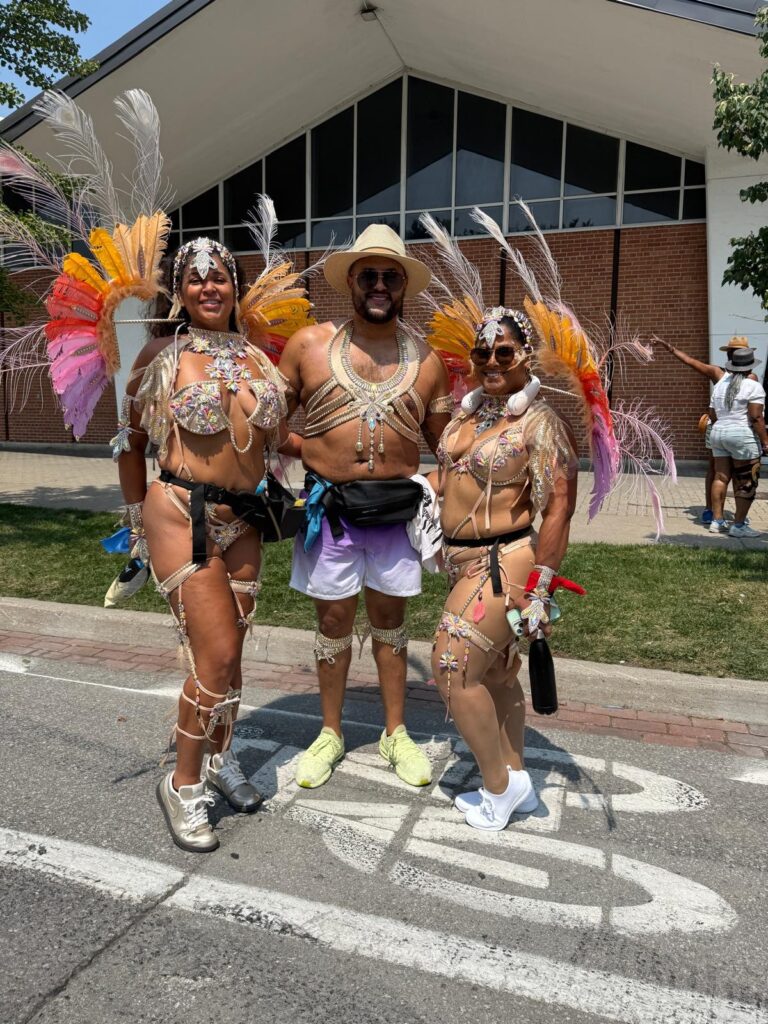 Three people in Carnival costumes pose for the camera.