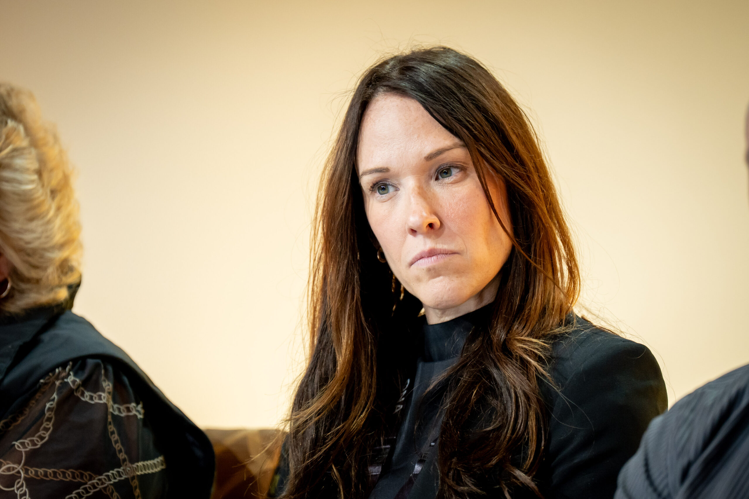 Woman speaks into microphone at table.