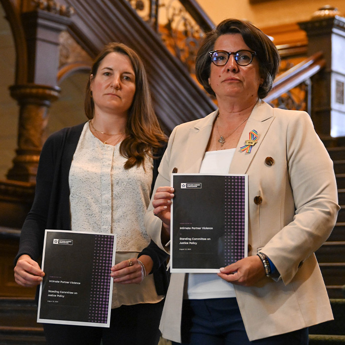 Provincial President Erin Ariss and member Michelle Bobala stand on the steps of Queen’s Park with an ONA submission on IPV in their hands.