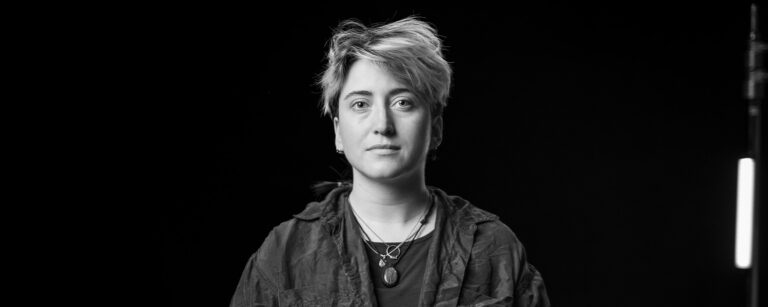 Black and white image of ONA member Hannah Stahl sitting and looking at camera.