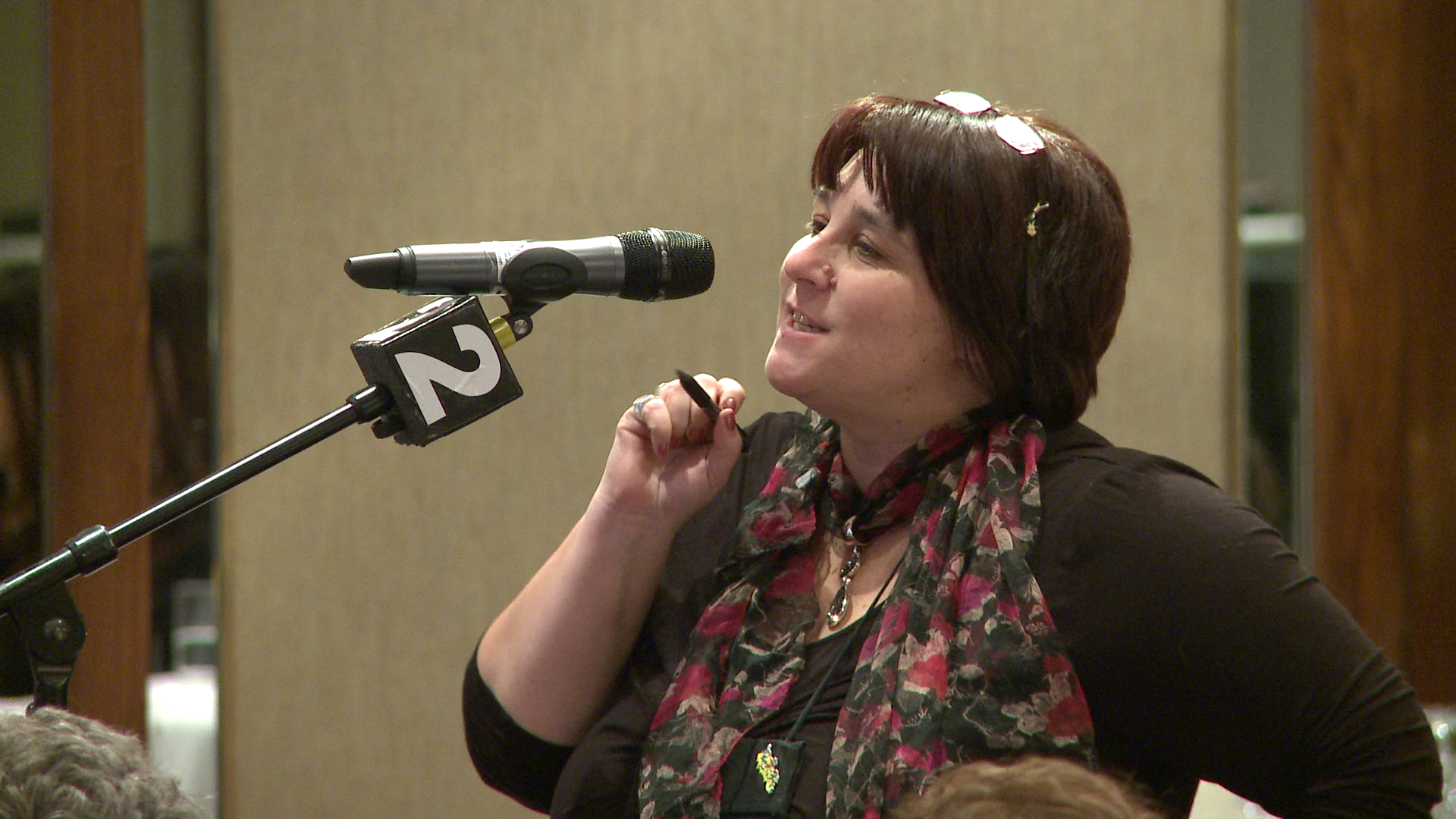 ONA member Dianne Leclair speaks into a floor microphone at a meeting.