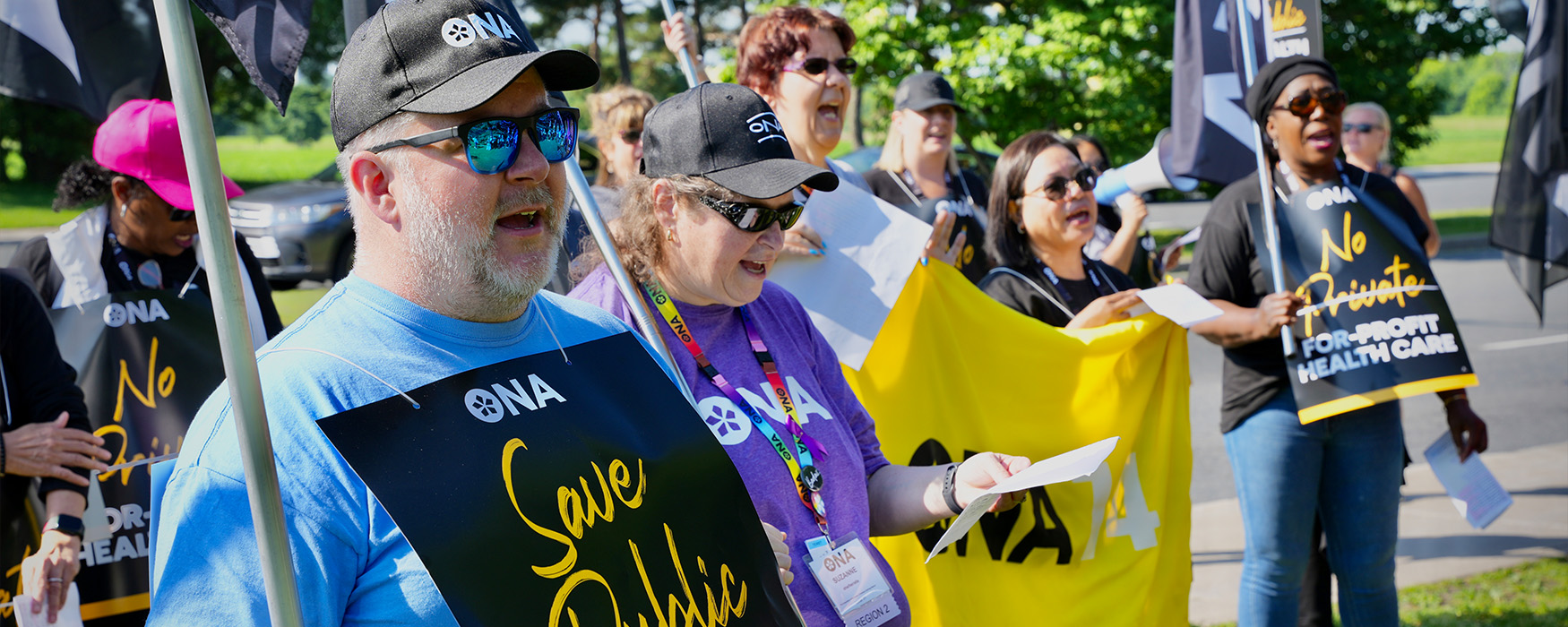 Region 5 Vice-President John Lowe wears a sign reading “Save Public Health Care” at a rally.
