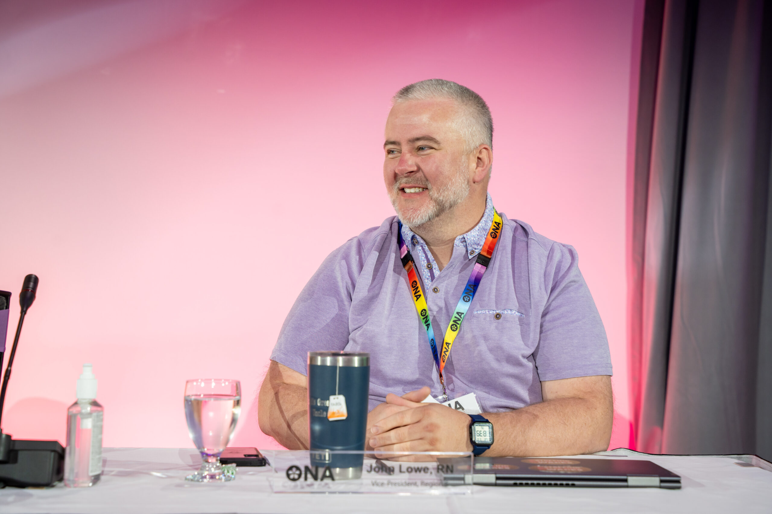 Region 5 Vice-President John Lowe sits at a table at a conference and smiles.
