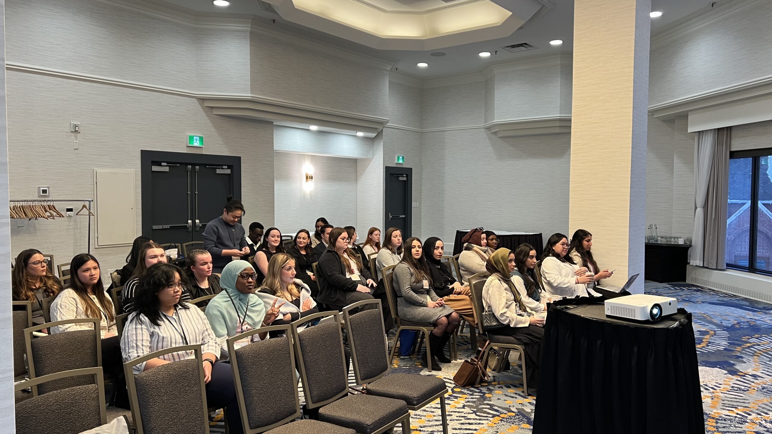 A group of students sit in a large meeting room.