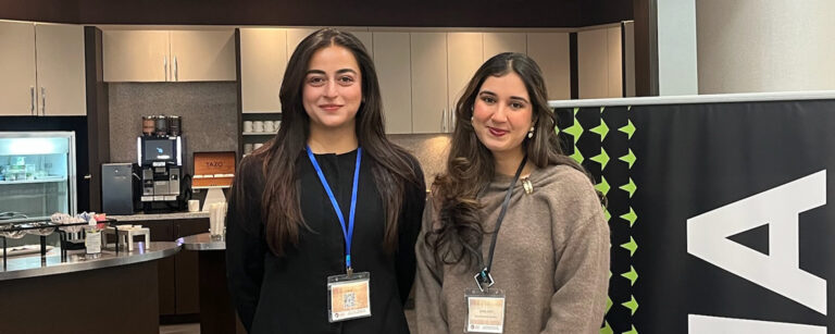 Recent grad Anika Joshi and an ONA staff member stand in front of a large ONA sign.