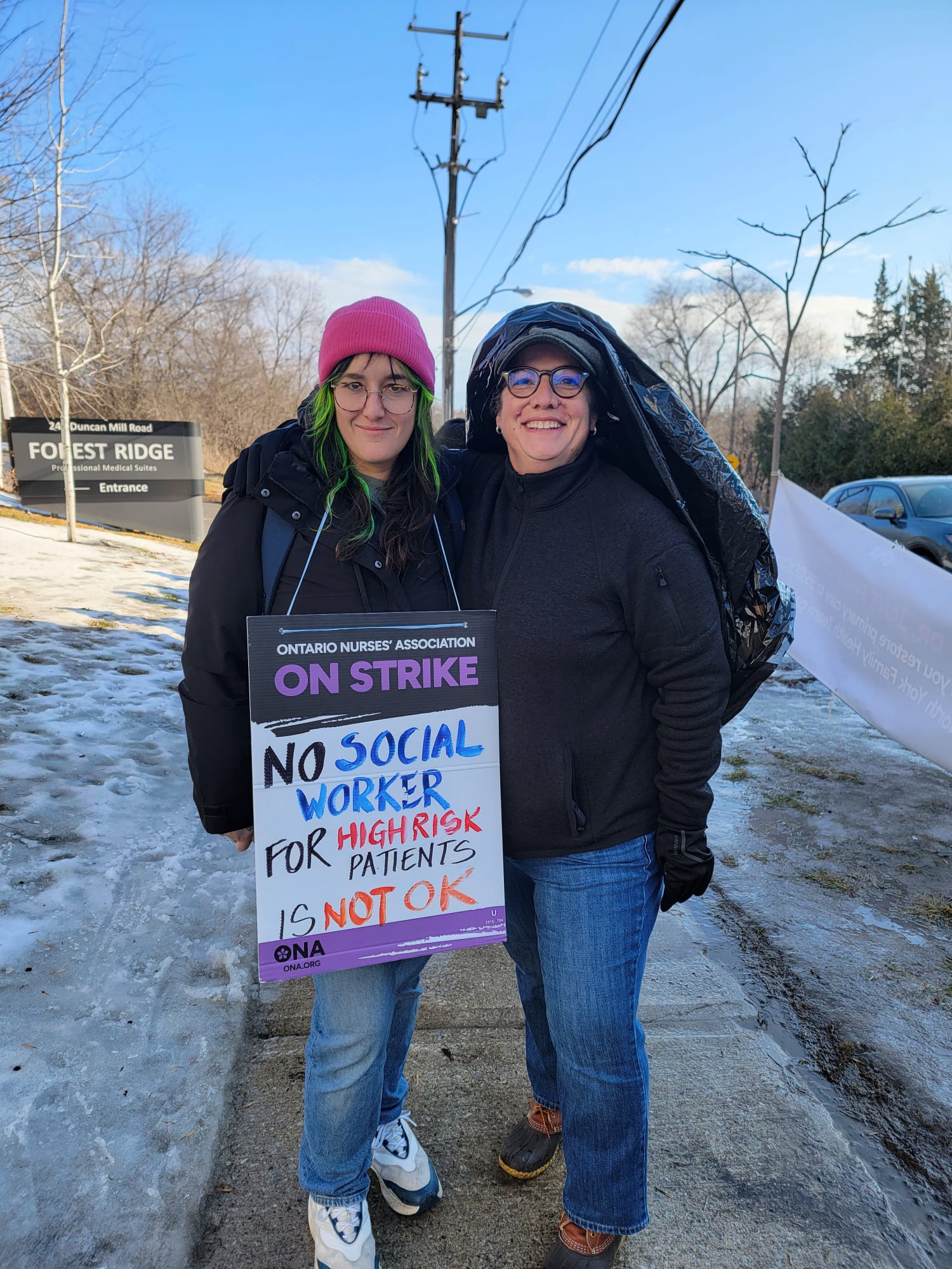 ONA member Emerald Lacaille stands with Provincial President Erin Ariss wearing a strike placard.