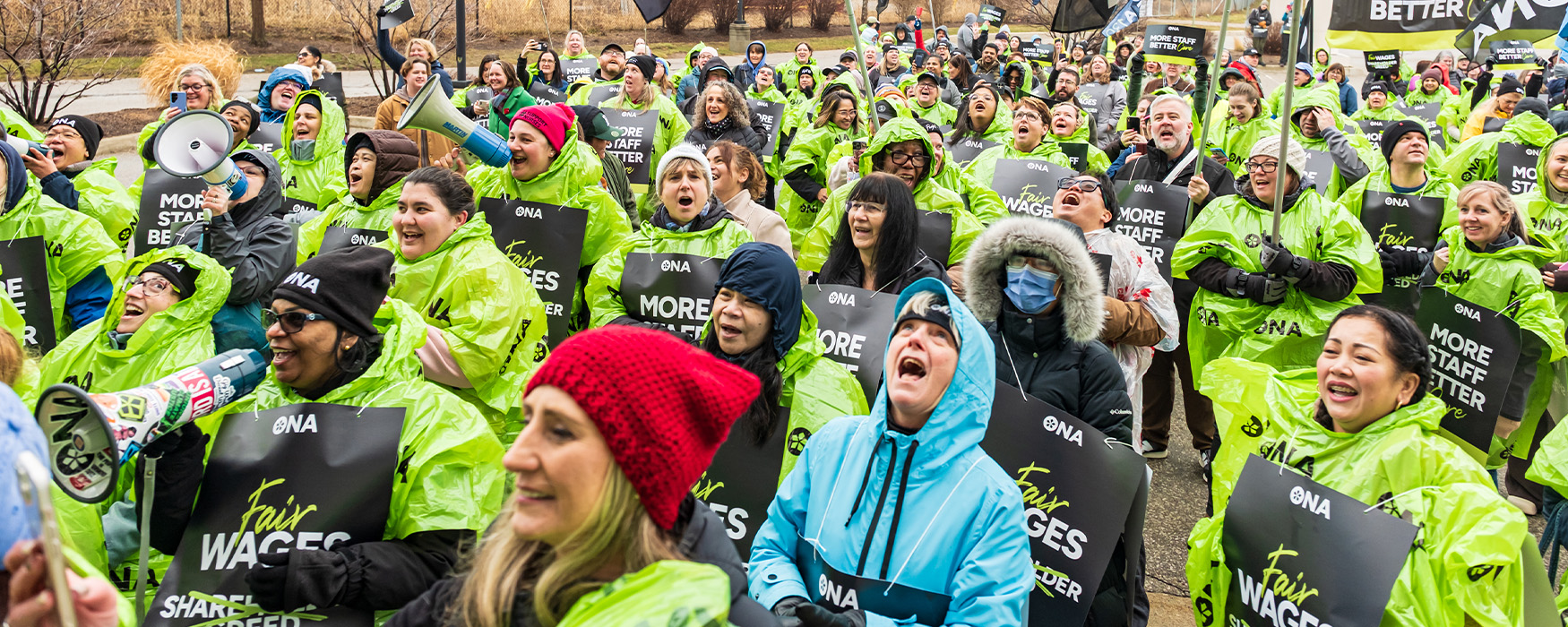 Large group of members cheer at rally in green rain ponchos.