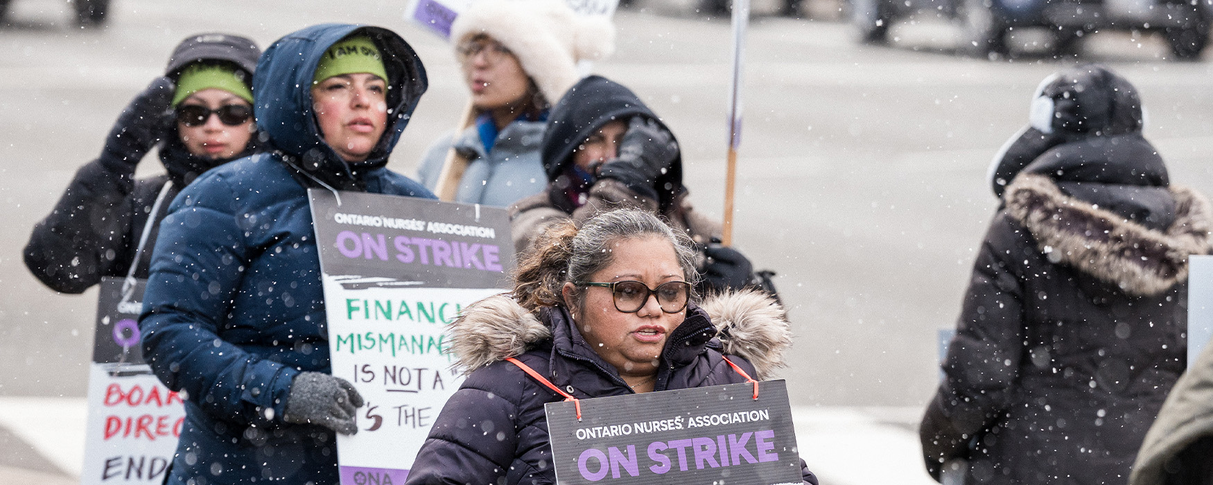 Group of members walk a picket line in the snow.