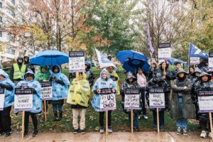 Members holding signs and wearing rain ponchos pose.