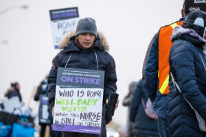 Man wears sign on picket line.