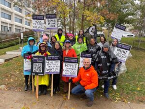 Politician allies and members in rain ponchos smile.