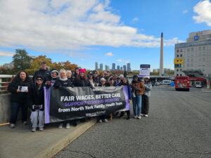 Members holding large banner pose outside a hospital.