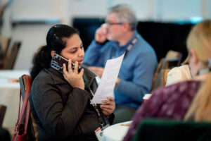 Woman sitting down reads script while on phone.