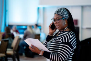 Woman standing reads script while on phone.