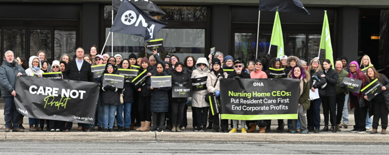 Group of ONA members stand together outside a hotel holding banners and flags.