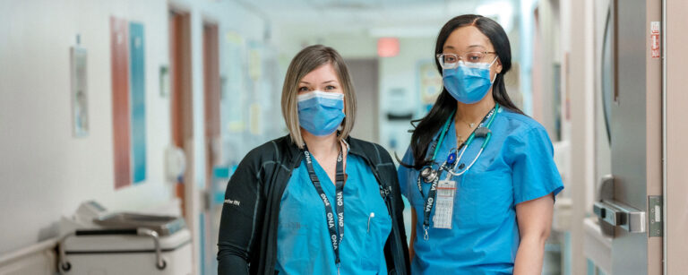 Two members stand side by side in scrubs.