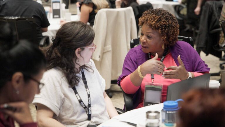 Two members talk at table.