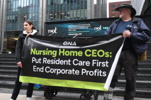 A member and ONA staffer hold a banner at rally.